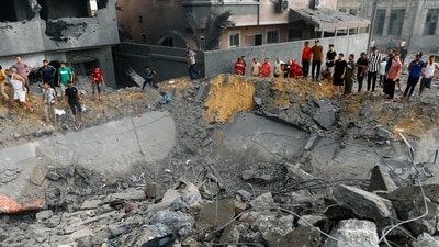 Palestinians gather around the rubble of a building destroyed in Israeli strikes, in the southern Gaza Strip October 9, 2023. (REUTERS)