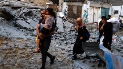 Palestinians carry their belongings as they walk on a debris-strewn street in the aftermath of Israeli strikes, following a Hamas surprise attack, at Beach refugee camp, in Gaza City, October 9, 2023. (Reuters)