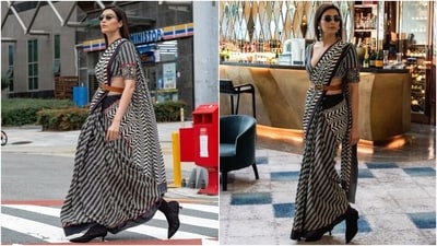 Karishma styled the saree with a matching half-sleeve blouse featuring a plunging V neckline, intricate embroidery on the sleeve borders, black and white leaf patterns, and a fitted design. A tan belt with the JJ Valaya logo cinched the saree under the torso, and a black trench coat gave the finishing touch. (Instagram) Karishma styled the saree with a matching half-sleeve blouse featuring a plunging V neckline, intricate embroidery on the sleeve borders, black and white leaf patterns, and a fitted design. A tan belt with the JJ Valaya logo cinched the saree under the torso, and a black trench coat gave the finishing touch. (Instagram)