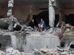 Palestinians sit among rubbles of a damaged residential building, in the aftermath of Israeli strikes, in Gaza City, October 10, 2023.