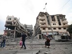 Palestinians carrying personal belongings walk past heavily damaged buildings following Israeli airstrikes on Gaza City's al-Rimal district on October 10. Palestinians carrying personal belongings walk past heavily damaged buildings following Israeli airstrikes on Gaza City's al-Rimal district on October 10.