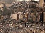 Israel-Palestine War: A Palestinian man talks on his mobile phone as he walks through a ravaged street. Israel-Palestine War: A Palestinian man talks on his mobile phone as he walks through a ravaged street.