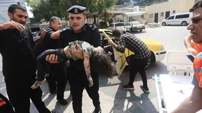 A Hamas police officer carries a wounded girl into a hospital in Beit Lahiya, Gaza Strip, on Sunday, (AP) A Hamas police officer carries a wounded girl into a hospital in Beit Lahiya, Gaza Strip, on Sunday, (AP)