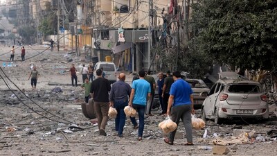 Palestinian men carry bread through a heavily bombed street following Israeli airstrikes on Gaza City on October 10, 2023. Israel kept up its deadly bombardment of Hamas-controlled Gaza on October 10 after the Palestinian militant group threatened to execute some of the around 150 hostages it abducted in a weekend assault if air strikes continue without warning. (AFP) Palestinian men carry bread through a heavily bombed street following Israeli airstrikes on Gaza City on October 10, 2023. Israel kept up its deadly bombardment of Hamas-controlled Gaza on October 10 after the Palestinian militant group threatened to execute some of the around 150 hostages it abducted in a weekend assault if air strikes continue without warning. (AFP)