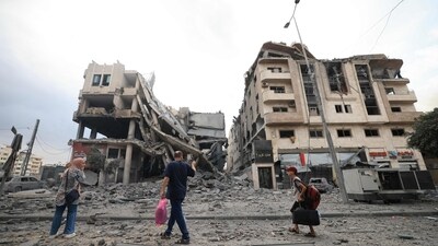 Palestinians carrying personal belongings walk past heavily damaged buildings following Israeli airstrikes on Gaza City's al-Rimal district on October 10. (AFP) Palestinians carrying personal belongings walk past heavily damaged buildings following Israeli airstrikes on Gaza City's al-Rimal district on October 10. (AFP)