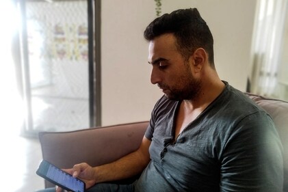 Yoni Asher, who saw videos of his wife, daughters, who are under five years old, and mother-in-law, surrounded by Hamas militants before his wife's phone was traced to Gaza, looks at his phone from his home in Ganot Hadar, Israel, (REUTERS)