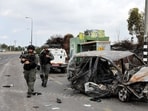 Israeli border police walk past a burnt out car as rockets are launched from the Gaza Strip towards Israel,
