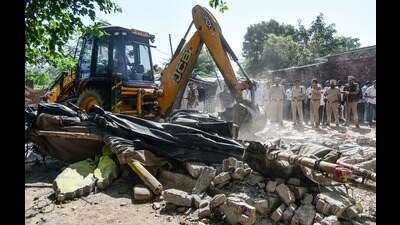 A bulldozer razing the illegal house of drug supplier. (HT Photo) A bulldozer razing the illegal house of drug supplier. (HT Photo)