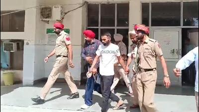 Gangster Sachin Bishnoi (centre) being escorted out of a Mansa court after he was brought from Delhi to Punjab recently for questioning in Punjabi singer Sidhu Moose Wala’s murder case. (HT file photo)