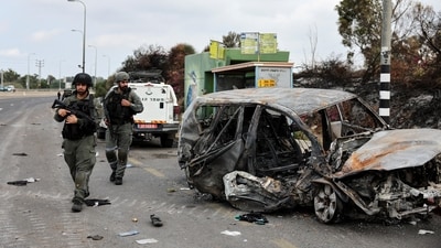 Israeli border police walk past a burnt out car as rockets are launched from the Gaza Strip towards Israel, (REUTERS)
