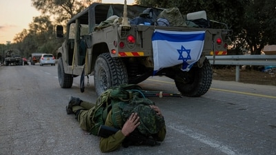 An Israeli soldier mistakenly thinks he hears an air raid siren and jumps to the ground to take cover in Kibbutz Be'eri, (AP)