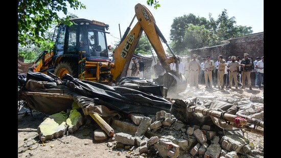 A bulldozer razing the illegal house of drug supplier. (HT Photo)
