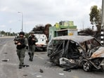 Israeli border police walk past a burnt out car as rockets are launched from the Gaza Strip towards Israel, in Ashkelon, southern Israel