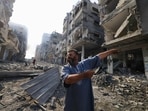 A Palestinian man points at destruction as people inspect the damage following overnight Israeli airstrikes in the Gaza Strip's Jabalia refugee camp on October 11, 2023.