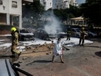 Israeli firefighters work to put out vehicles on fire after a rocket, launched from the Gaza Strip, landed in Ashkelon, southern Israel