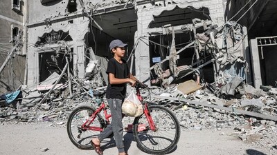 A Palestinian child carries bread as he pushes his bike amid the rubble of buildings destroyed in an Israeli air strike in Rafah. (AFP) A Palestinian child carries bread as he pushes his bike amid the rubble of buildings destroyed in an Israeli air strike in Rafah. (AFP)