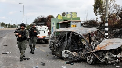 Israeli border police walk past a burnt out car as rockets are launched from the Gaza Strip towards Israel, in Ashkelon, southern Israel (REUTERS)
