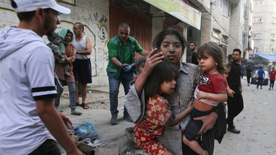 A Palestinian girl holds two children as she stands on a street in Gaza City on October 12, 2023 as raging battles between Israel and the Hamas movement continue for the sixth consecutive day. (AFP) A Palestinian girl holds two children as she stands on a street in Gaza City on October 12, 2023 as raging battles between Israel and the Hamas movement continue for the sixth consecutive day. (AFP)