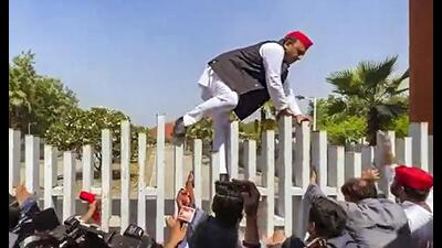Samajwadi Party chief Akhilesh Yadav climbs a wall while trying to enter Jai Prakash Narayan International Centre to offer floral tribute to the statue of Jai Prakash Narayan on his birth anniversary, in Lucknow, Wednesday. (PTI Photo)