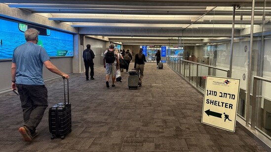 People walk next to a sign directing for Shelter after landing in Israel at the arrivals section of Ben Gurion International.