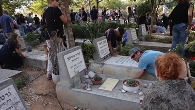 CORRECTION / Mourners duck for cover upon hearing sirens warning of incoming rockets during the funeral of Tom Godo, killed during the attack by Palestinian Hamas militants on the Kibbutz Kisuffim last week, in Kibbutz Naan near Tel Aviv on October 13, 2023. Thousands of people, both Israeli and Palestinians have died since October 7, 2023, after Palestinian Hamas militants entered Israel in a surprise attack leading Israel to declare war on Hamas in the Gaza Strip on October 8. (AFP) CORRECTION / Mourners duck for cover upon hearing sirens warning of incoming rockets during the funeral of Tom Godo, killed during the attack by Palestinian Hamas militants on the Kibbutz Kisuffim last week, in Kibbutz Naan near Tel Aviv on October 13, 2023. Thousands of people, both Israeli and Palestinians have died since October 7, 2023, after Palestinian Hamas militants entered Israel in a surprise attack leading Israel to declare war on Hamas in the Gaza Strip on October 8. (AFP)