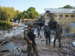 Israel-Hamas War: Israeli soldiers walk past houses destroyed by Hamas militants in Kibbutz Be'eri, Israel. Israel-Hamas War: Israeli soldiers walk past houses destroyed by Hamas militants in Kibbutz Be'eri, Israel.