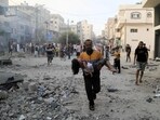 A Palestinian carrying a child runs following an Israeli strike in Khan Yunis in the southern Gaza Strip on October 14. A Palestinian carrying a child runs following an Israeli strike in Khan Yunis in the southern Gaza Strip on October 14.