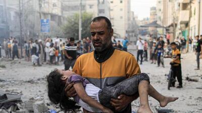 A Palestinian man carries an injured a girl following an Israeli strike, in Khan Yunis in the southern Gaza Strip on October 14, 2023, as fighting between Israel and the Hamas movement continues for the eighth consecutive day. (AFP)