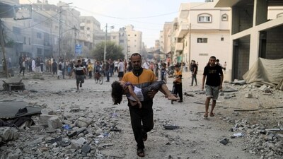 A Palestinian carrying a child runs following an Israeli strike in Khan Yunis in the southern Gaza Strip on October 14. (AFP) A Palestinian carrying a child runs following an Israeli strike in Khan Yunis in the southern Gaza Strip on October 14. (AFP)
