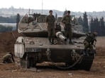 Israeli soldiers stand atop an Israeli tank near Israel's border with the Gaza Strip. 