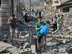 Palestinians walk through the rubble of buildings destroyed by Israeli airstrikes in Gaza City October 10. Palestinians walk through the rubble of buildings destroyed by Israeli airstrikes in Gaza City October 10.