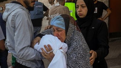 A Palestinian woman kisses the sheet-covered body of a child killed during an Israeli airstrike (AP) A Palestinian woman kisses the sheet-covered body of a child killed during an Israeli airstrike (AP)