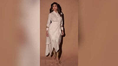 Shilpa Shetty's indo western look in a stunning white gown is a must have for your festive wardrobe. A perfect blend of modern and traditional style, this unique ensemble is sure to make you the centre of attention at the Day 2 garba party. It features a white wrap dress with full sleeves, a belt at the waist and an asymmetric hem. Gold trousers, matching bangles and gold statement earrings add the oomph factor to her look. Shilpa's glamorous look was completed with kohl-rimmed eyes, contoured cheeks, nude lipstick and loose hair. (Instagram/@theshilpashetty) Shilpa Shetty's indo western look in a stunning white gown is a must have for your festive wardrobe. A perfect blend of modern and traditional style, this unique ensemble is sure to make you the centre of attention at the Day 2 garba party. It features a white wrap dress with full sleeves, a belt at the waist and an asymmetric hem. Gold trousers, matching bangles and gold statement earrings add the oomph factor to her look. Shilpa's glamorous look was completed with kohl-rimmed eyes, contoured cheeks, nude lipstick and loose hair. (Instagram/@theshilpashetty)
