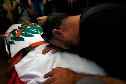 A friend of Reuters videographer Issam Abdallah, who was killed by Israeli shelling, mourns over his body during his funeral procession in his hometown of Khiam, southern Lebanon, on Saturday. (AP)
