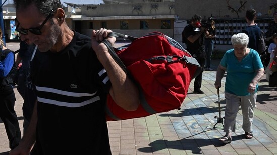 Israel-Hamas War: Israelis wait to board a bus as they are evacuated from the southern Israeli city of Sderot to safer areas in the state of Israel. (AFP)