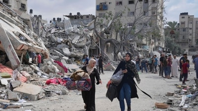 Palestinian women walk by buildings destroyed in Israeli airstrikes in Nuseirat camp in the central Gaza Strip, Monday, Oct. 16, 2023. AP/PTI(AP10_16_2023_000107A) (AP) Palestinian women walk by buildings destroyed in Israeli airstrikes in Nuseirat camp in the central Gaza Strip, Monday, Oct. 16, 2023. AP/PTI(AP10_16_2023_000107A) (AP)