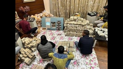 Income Tax officials with cash recovered during tax evasion searches against some Karnataka-based contractors and persons linked to them, in Bengaluru on Friday. (PTI) Income Tax officials with cash recovered during tax evasion searches against some Karnataka-based contractors and persons linked to them, in Bengaluru on Friday. (PTI)