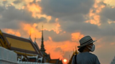 A tourist wears a face mask to prevent spread of the coronavirus disease (Covid-19) during sunset near the Grand Palace in Bangkok, Thailand. (Reuters)