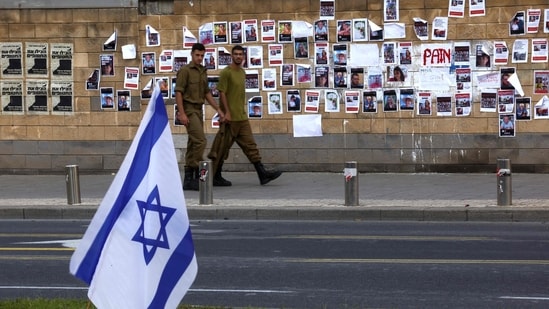 Israel-Hamas War: Israeli soldiers walk past images of Israeli hostages snatched by the Palestinian militant group Hamas last week in a surprise attack into Israel. (AFP)