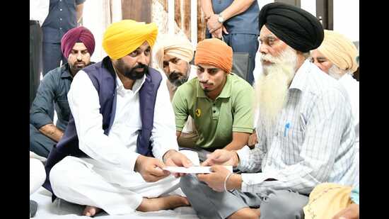Punjab CM Bhagwant Mann handing over a ₹1-crore cheque to kin of sepoy Parvinder Singh, who died at Kargil recently. (HT Photo)