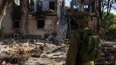 Israel-Hamas War: An Israeli soldier stands in front of a burnt house on October 17, 2023 in Kibbutz Beeri near the border with Gaza. (AFP) Israel-Hamas War: An Israeli soldier stands in front of a burnt house on October 17, 2023 in Kibbutz Beeri near the border with Gaza. (AFP)