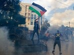 A protester waves a Palestinian flag as riot police use tear gas during a demonstration in solidarity with the Palestinian people in Gaza, near the U.S. embassy in Aukar, a northern suburb of Beirut, Lebanon. A protester waves a Palestinian flag as riot police use tear gas during a demonstration in solidarity with the Palestinian people in Gaza, near the U.S. embassy in Aukar, a northern suburb of Beirut, Lebanon.