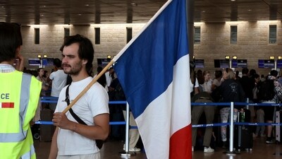 A man holds the French flag as French nationals leaving Israel for France check-in at Ben Gurion International Airport. (AFP) A man holds the French flag as French nationals leaving Israel for France check-in at Ben Gurion International Airport. (AFP)