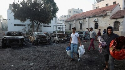 People walk with their belongings in the area of Al-Ahli hospital where hundreds of Palestinians were killed in a blast that Israeli and Palestinian officials blamed on each other, and where Palestinians who fled their homes were sheltering amid the ongoing conflict with Israel,  in Gaza City, October 18, 2023.  REUTERS/Mohammed Al-Masri)