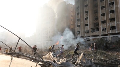 Israel-Hamas War: Palestinians run by the building destroyed in an Israeli airstrike on Nusseirat refugee camp, Gaza Strip. (AP) Israel-Hamas War: Palestinians run by the building destroyed in an Israeli airstrike on Nusseirat refugee camp, Gaza Strip. (AP)