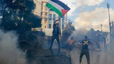 A protester waves a Palestinian flag as riot police use tear gas during a demonstration in solidarity with the Palestinian people in Gaza, near the U.S. embassy in Aukar, a northern suburb of Beirut, Lebanon. (AP)