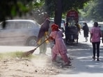 Sanitation staff sweep a road in Sector 31 in Gurugram on Wednesday. (Parveen Kumar/HT Photo)