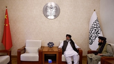 Taliban's acting commerce minister Haji Nooruddin Azizi sits next to flags of the Islamic Emirate of Afghanistan and China. (REUTERS)