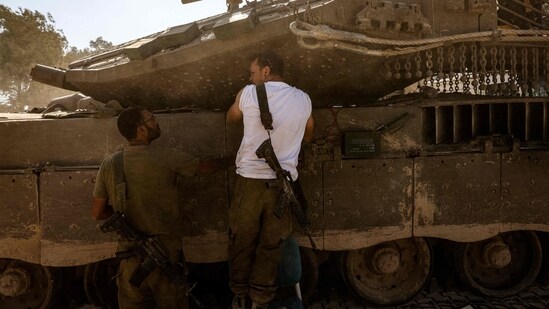 Israeli soldiers chat as they take position outside Kibbutz Beeri near the border with the Gaza Strip. (AFP)
