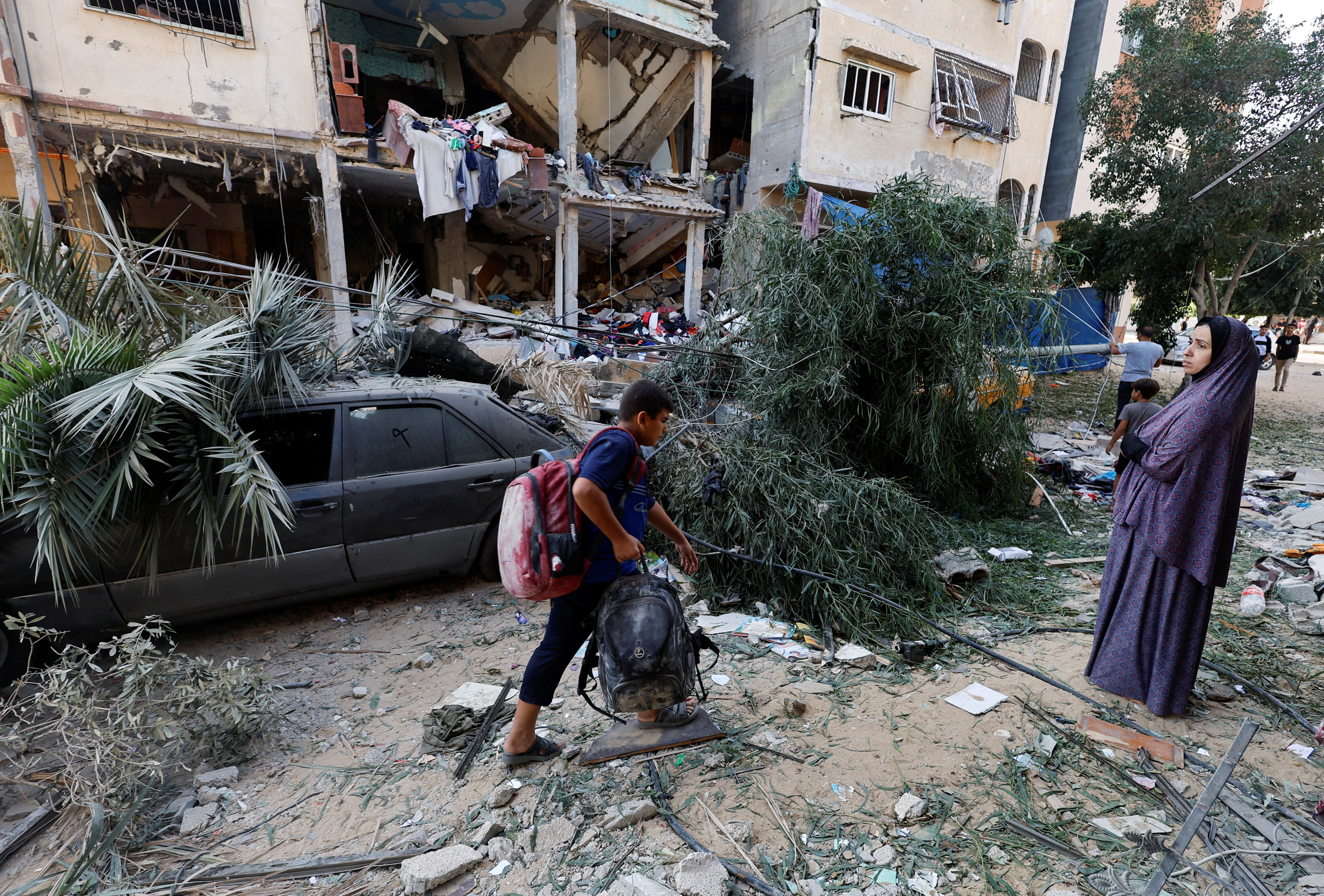 A Palestinian boy walks with his belongings at the site of Israeli strikes on a house, amid the ongoing conflict between Israel and Palestinian Islamist group Hamas, in Khan Younis, southern Gaza Strip October 20, 2023.  (REUTERS)